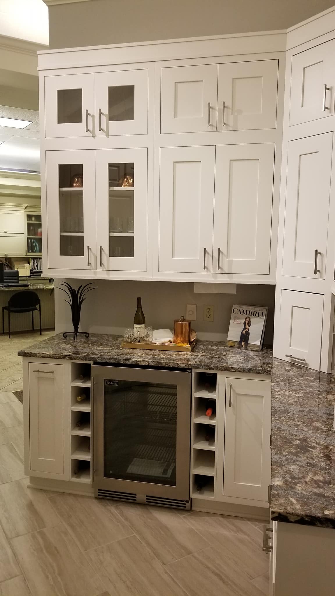 showroom cabinets display of glass front and white cabinets, wine cooler, granite countertop | Marchand Creative Kitchens Cabinets New Orleans Metairie Mandeville LA